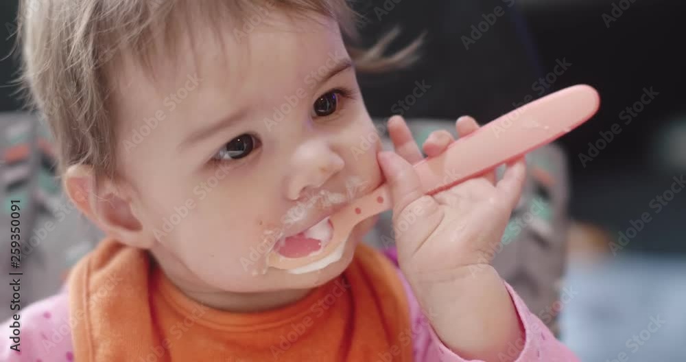 4K Cinematic portrait of a 10 month old baby girl being spoon fed yogurt. Real life, candid footage. 4K Cinematic portrait of a 10 month old baby girl being spoon fed yogurt. Real life, candid footage.
