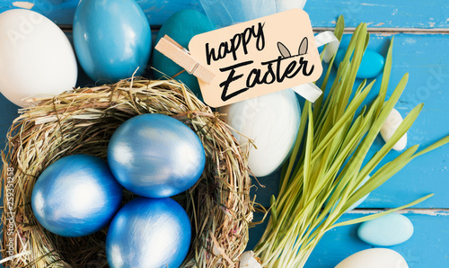 Bright blue colored Easter eggs in nest on wooden background, selective focus image. Happy Easter card  