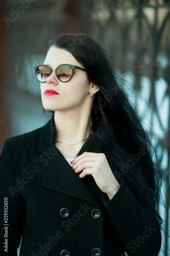Young woman posing in black coat and black hat. © hamara
