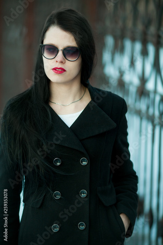 Young woman posing in black coat and black hat. © hamara