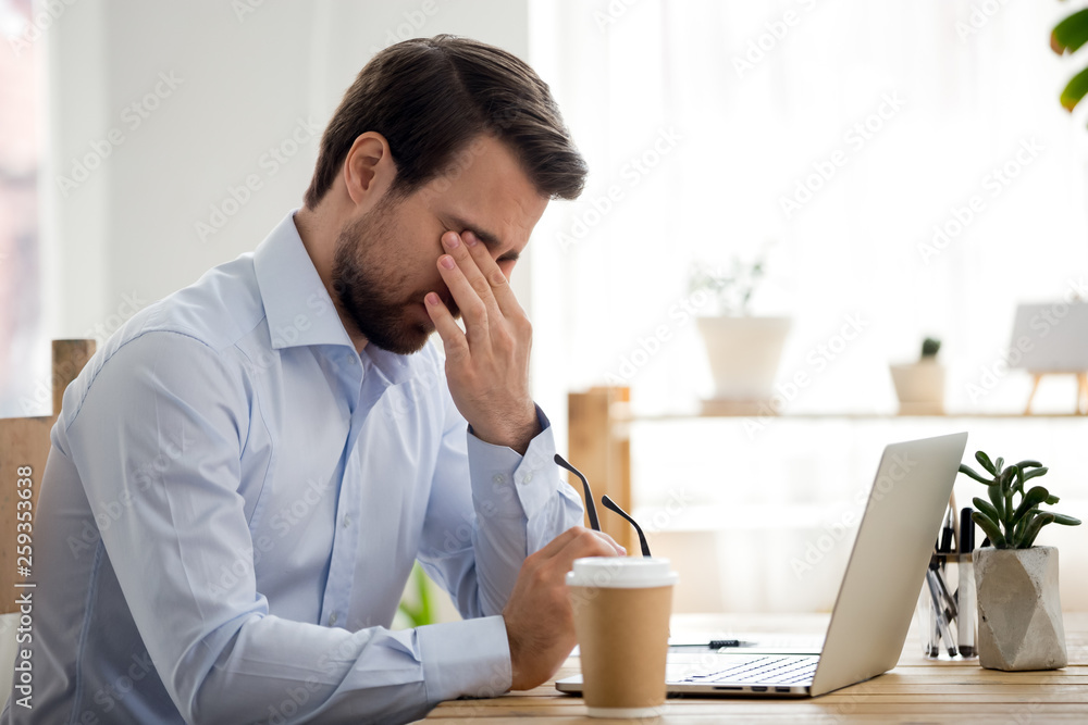 Tired worker sitting at the desk in office Tired worker sitting at the desk in office
