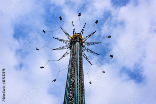Photography Austria, Vienna, Prater: High spinning swing carousel at full speed action from below in famous public park of the Austrian capital with blue cloudy sky