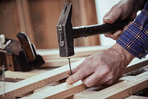 Carpenter hammering in a nail with vintage hammer