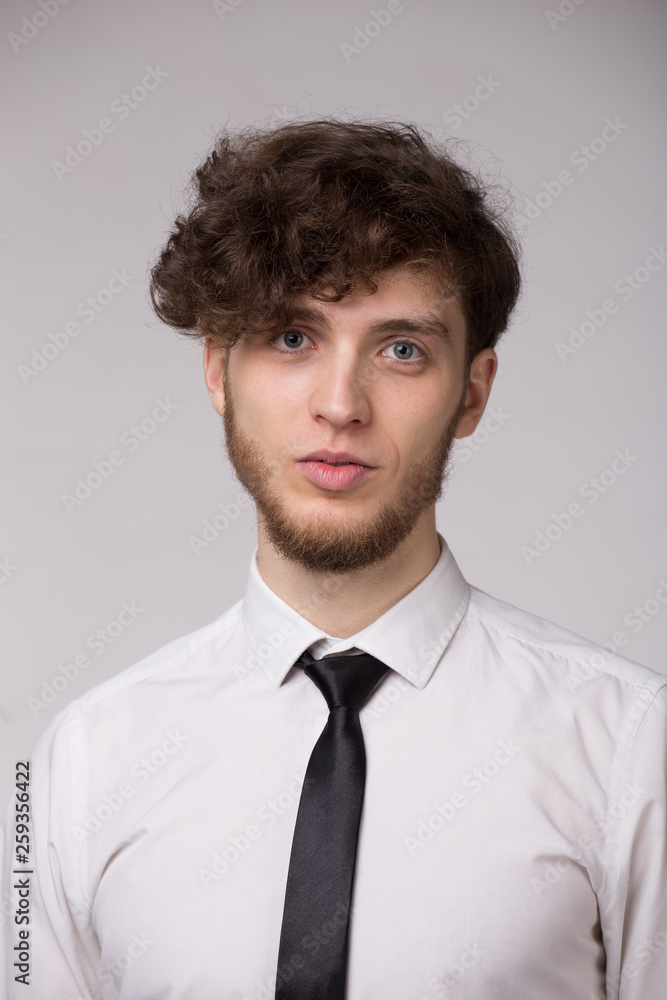 Confident young man in shirt smiling and looking at camera over gray background Confident young man in shirt smiling and looking at camera over gray background