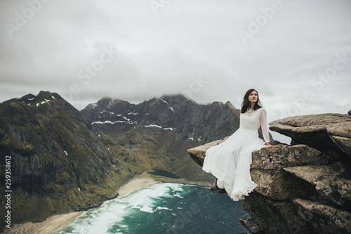 Wedding couple travelers on a hill in Norway, Kvalvika. Beautiful view of the beach, Lofoten, Norway. photo