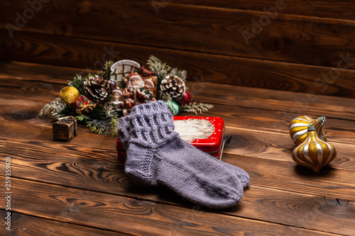 gray knitted socks, Christmas decorations and a metal box with the image of Santa Claus on a wooden background