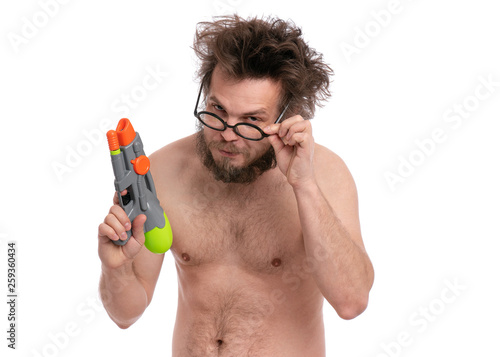 Crazy bearded Man with funny Haircut in eyeglasses, ready for fun at sunny beach. Happy and silly tourist, isolated on white background. Cheerful naked man holding Water Gun.