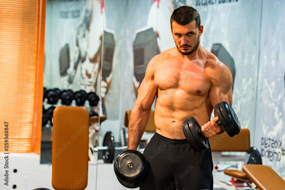 Male athlete doing biceps exercise with dumbbells Male athlete doing biceps exercise with dumbbells