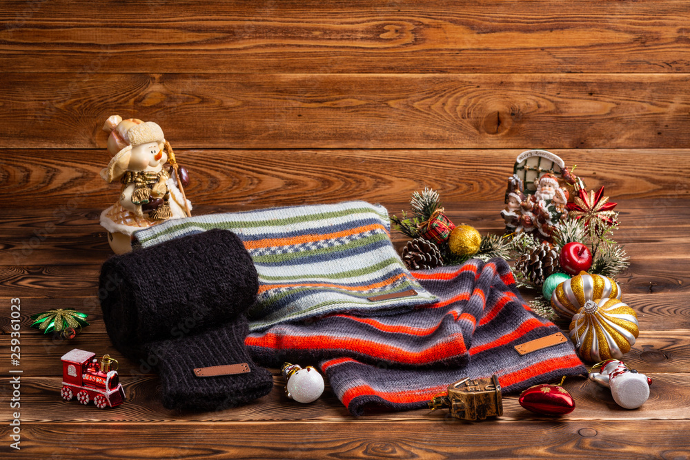 knitted striped striped scarves, black knitted sleeves and Christmas toys on wooden background