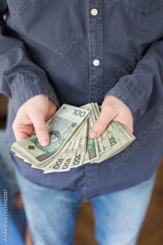 Unemployed man counting money from polish social benefits.