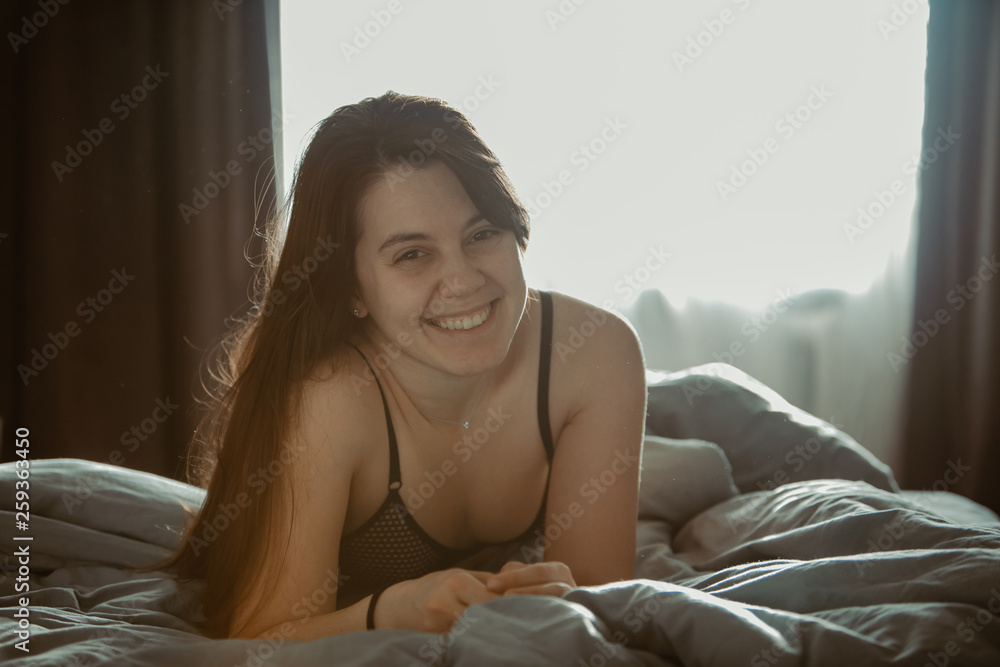 young pretty woman in black bra sitting on bed. morning time young pretty woman in black bra sitting on bed. morning time