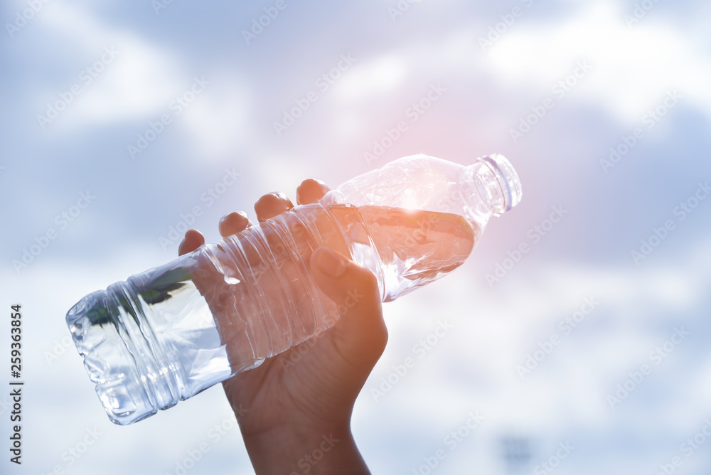 Woman hand holding a drinking water bottle on blue sky background in the  morning with sunlight. Cool drinking water. World Water Day concept. Stock  Photo | Adobe Stock