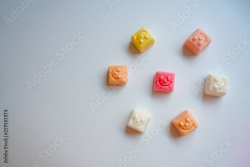 delicious square bright candy with smile on white background