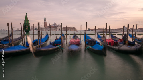 Gondolas and gondolier in lagoon of Venice by Saint Mark (San Marco) square with San Giorgio di Maggiore church in background in Venice