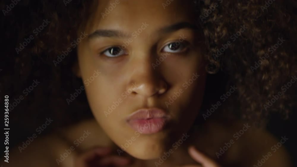 Handheld portrait shot with lose up of beautiful young black woman covering her bare chest with her arms and looking at camera Handheld portrait shot with lose up of beautiful young black woman covering her bare chest with her arms and looking at camera