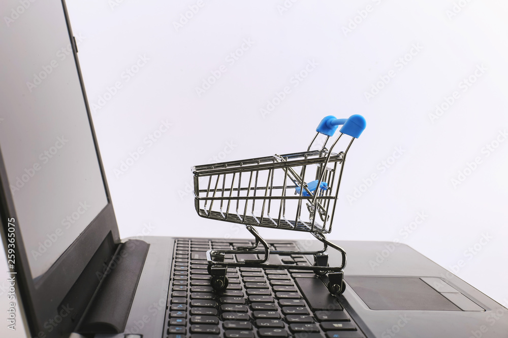 Shopping cart is on the laptop. Online sales concept.