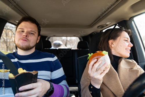 young couple eating fast food in car