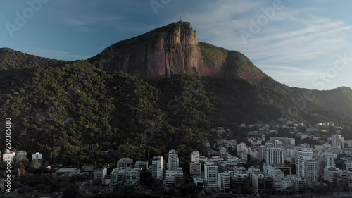 Slow approach of the Corcovado mountain in Rio de Janeiro with the Christ statue on top of it at sunrise in the middle of the Tijuca National Park. Famous tourist attraction and Christianity symbol. photo