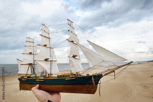 Fototapeta Naklejka Na Ścianę i Meble -  Scale model of a wooden sailing ship on the coast of the Baltic Sea on a cloudy spring day