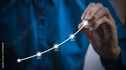 Businessman using pen drawing graphics line year growing graph.