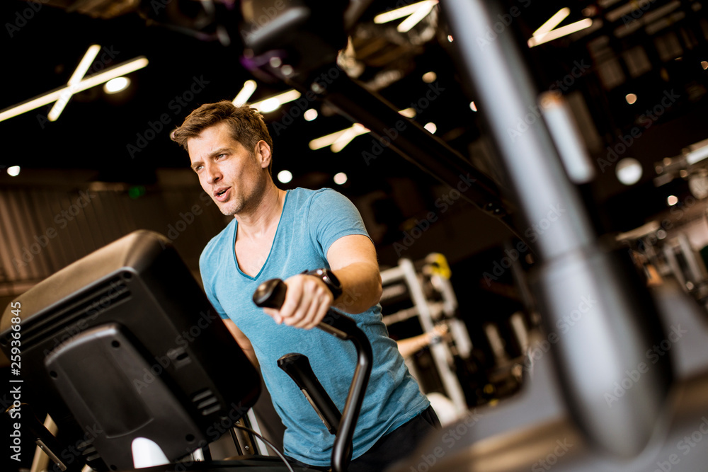 Man doing exercise on elliptical cross trainer in sport fitness gym club Man doing exercise on elliptical cross trainer in sport fitness gym club