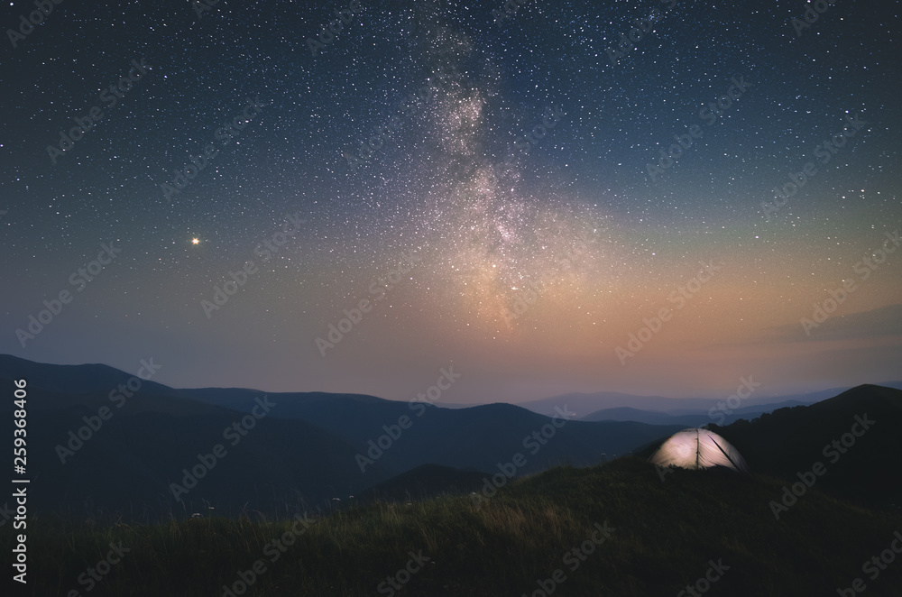 Illuminated white camping tent under stars with Milky Way in the Ukraine, Carpathians Borjava Ridge