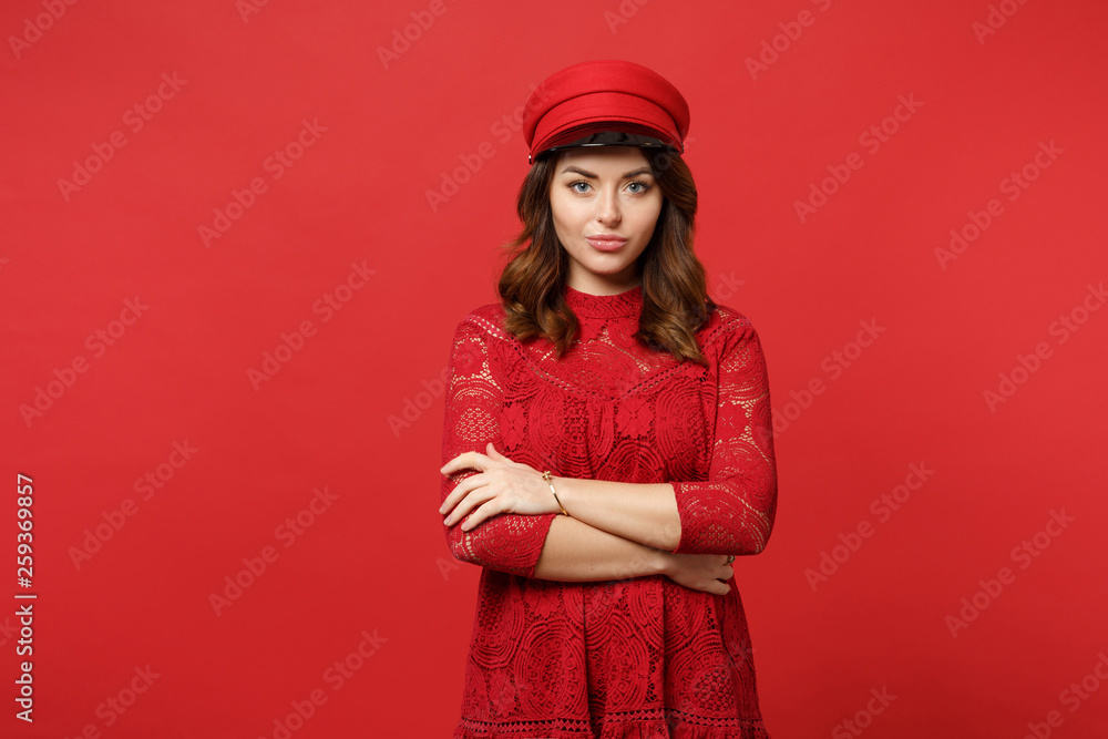 Portrait of pretty young woman in lace dress and cap looking camera, holding hands crossed isolated on bright red background in studio. People sincere emotions, lifestyle concept. Mock up copy space. Portrait of pretty young woman in lace dress and cap looking camera, holding hands crossed isolated on bright red background in studio. People sincere emotions, lifestyle concept. Mock up copy space.