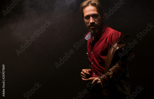 A man on a black background dancing in the smoke. Model tests in low key. Adult man grins in dynamics