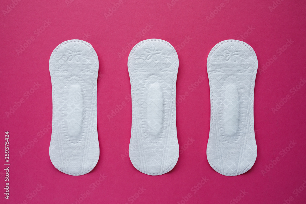 Feminine hygiene pad on a pink background. Concept of feminine hygiene during menstruation. Flat lay, top view. Feminine hygiene pad on a pink background. Concept of feminine hygiene during menstruation. Flat lay, top view.