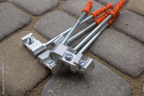 bolt fastening for gutter pipes,New bolts lie on the cobblestone for fixing gutter plastic pipes