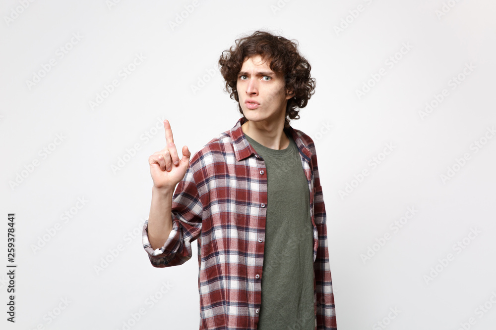 Portrait of perplexed young man in casual clothes looking camera, pointing index finger up isolated on white wall background in studio. People sincere emotions, lifestyle concept. Mock up copy space. Portrait of perplexed young man in casual clothes looking camera, pointing index finger up isolated on white wall background in studio. People sincere emotions, lifestyle concept. Mock up copy space.