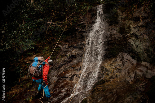 Young man dulfers down the mountain with waterfall in Adjara