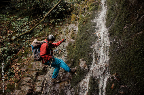 Young man dulfers down the mountain with waterfall in Adjara