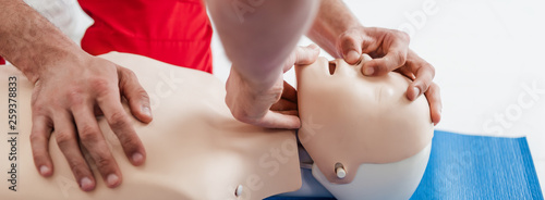 panoramic shot of men practicing cpr technique on dummy during first aid training photo