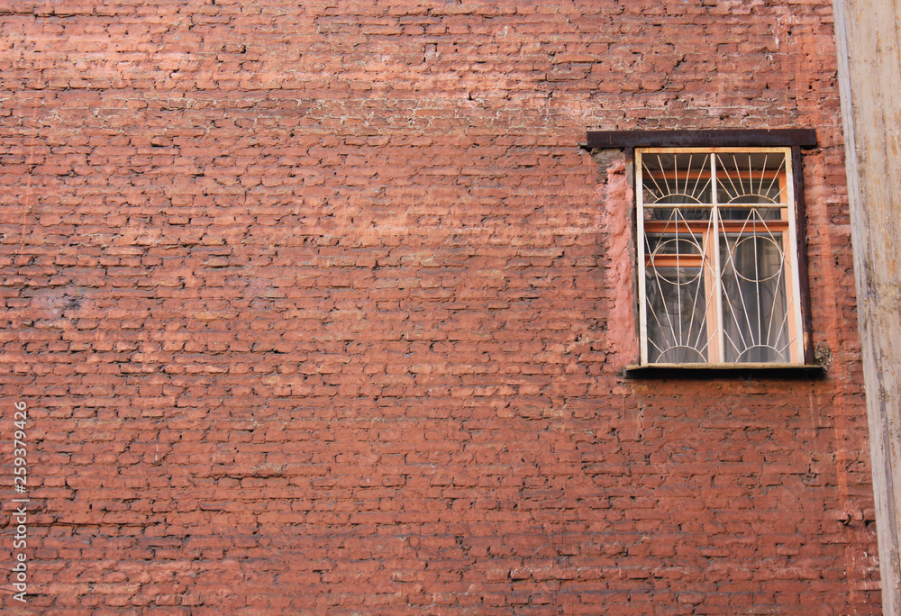 Window on brick wall of old building facade. Rural countryside, suburbs and neighbourhood architecture of rustic house with only one window with bars and empty brickwall background