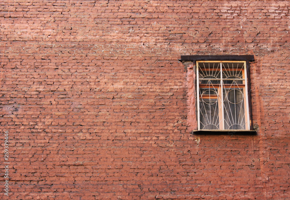 Brick house wall with single window on old building facade exterior. Rural suburbs architecture of rustic house and last window with bars on empty brickwall and stone structure background