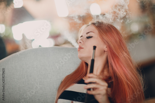 Young beautiful female smoking hookah. Smoke shisha hookah concept.
