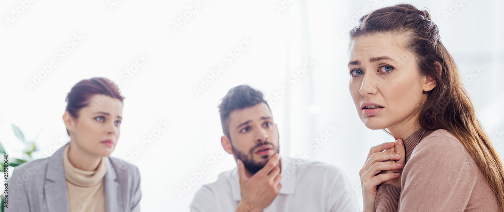 panoramic shot of worried woman looking at camera during group therapy session panoramic shot of worried woman looking at camera during group therapy session