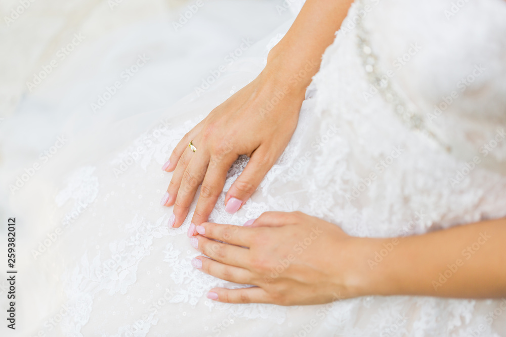 White, beige wedding dress with hands relaxing. Bride, wedding background concept