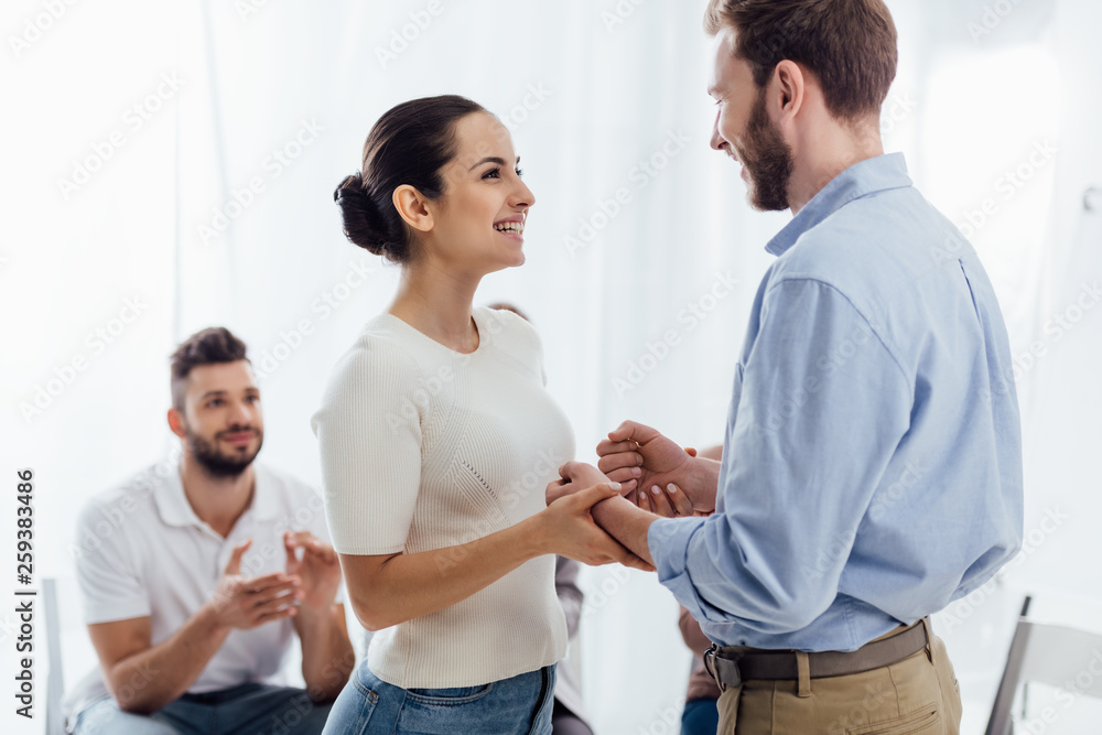 Fototapeta premium beautiful smiling woman holding hands with man during group therapy session