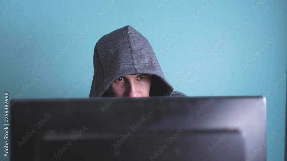 man hacker in the hood hacking network concept. unknown lifestyle hacker criminal breaks into computer protection on the Internet passwords. male hacker penetrates into hack network protection web