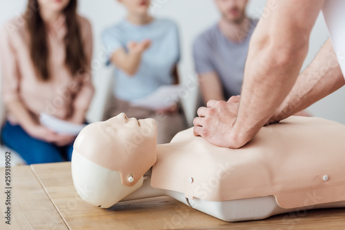 cropped view of instructor performing chest compression on dummy during cpr training class