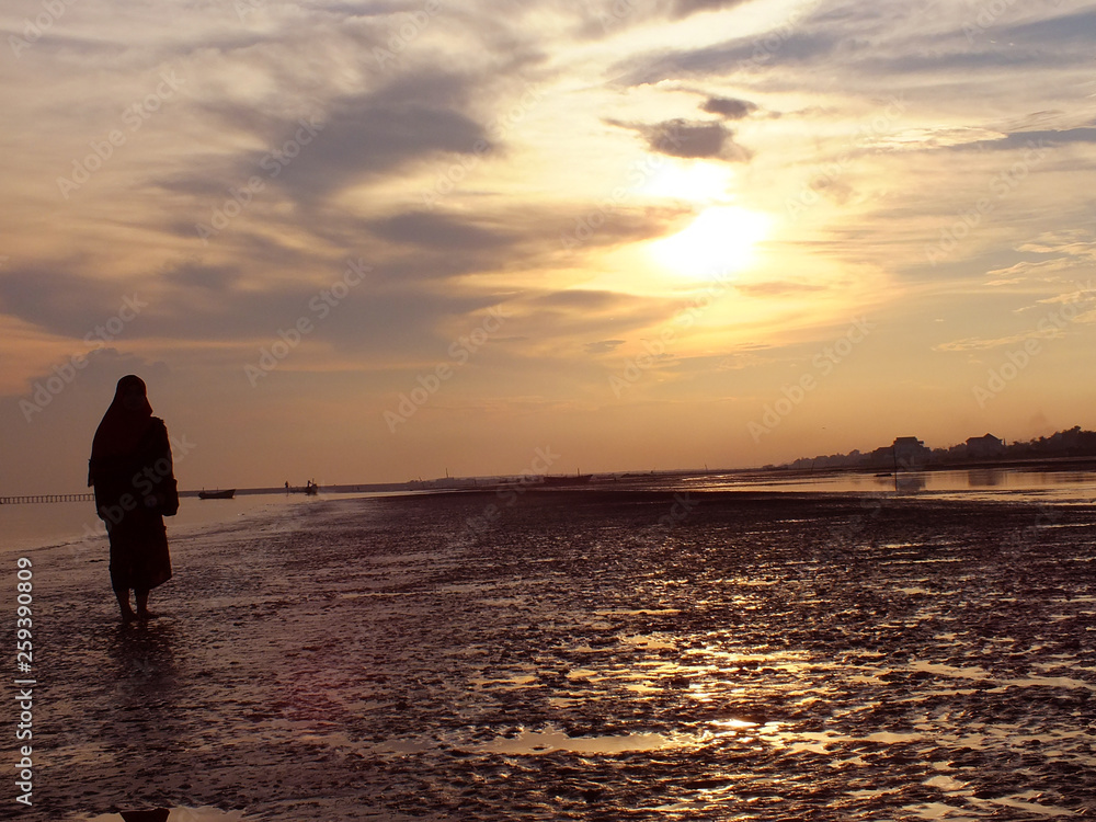 silhouette of muslim women on the beach at sunset