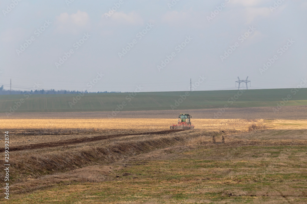 tractor plows the field in early spring for sowing crops. Agriculture of Belarus.