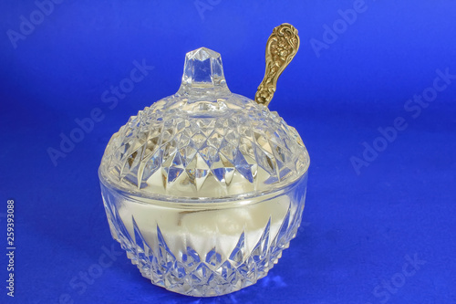 Antique cut-glass crystal sugar bowl and antique sterling silver sugar spoon against rich blue BG photo