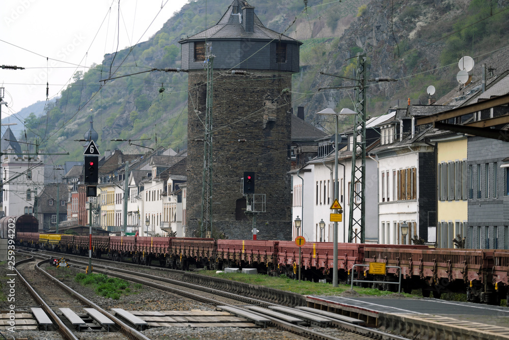 Fototapeta premium Güterzug auf der Rheinstrecke bei Kaub nahe an Häuserreihe mit Bahnlärm im Mittelrheintal - Stockfoto