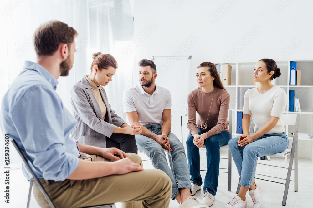 people in casual clothes sitting on chairs during support group session people in casual clothes sitting on chairs during support group session