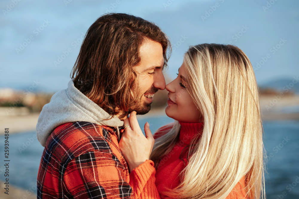 Young couple on the beach hugging and looking at each other with love. Holidays at sea on vacation. Portrait at sunset. Young couple on the beach hugging and looking at each other with love. Holidays at sea on vacation. Portrait at sunset.