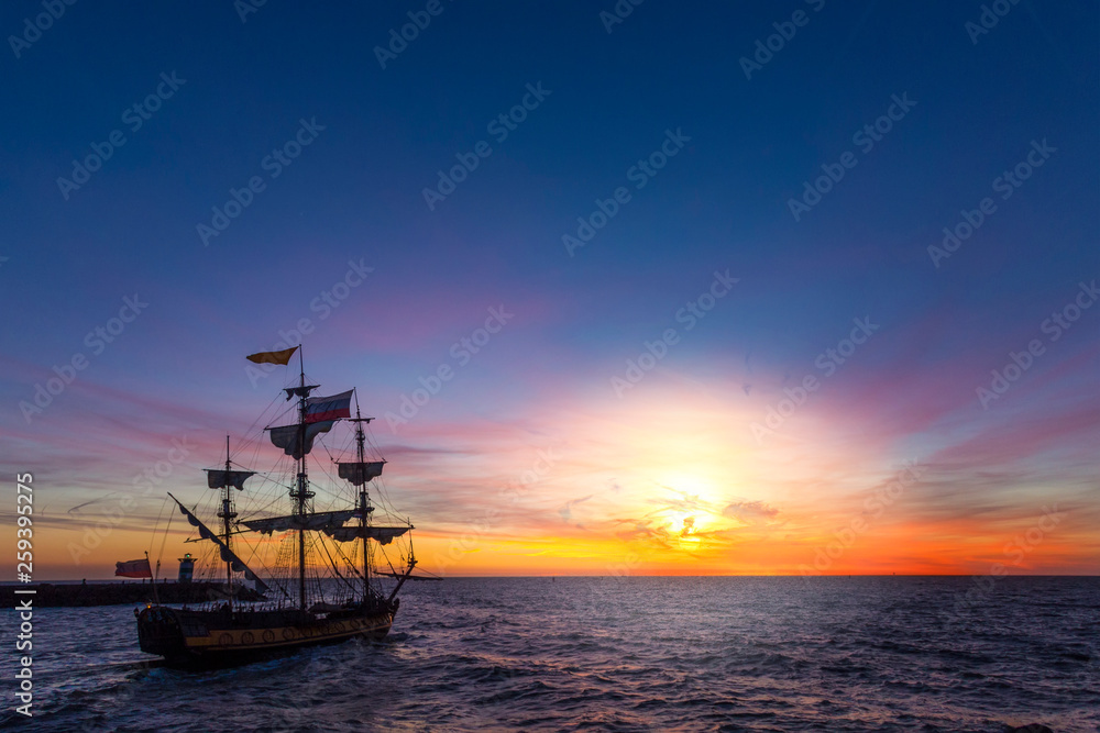 Silhouette of a pirate ship leaving the harbor for a long campaign on the ocean chasing, pirating other marchand ship with copy space