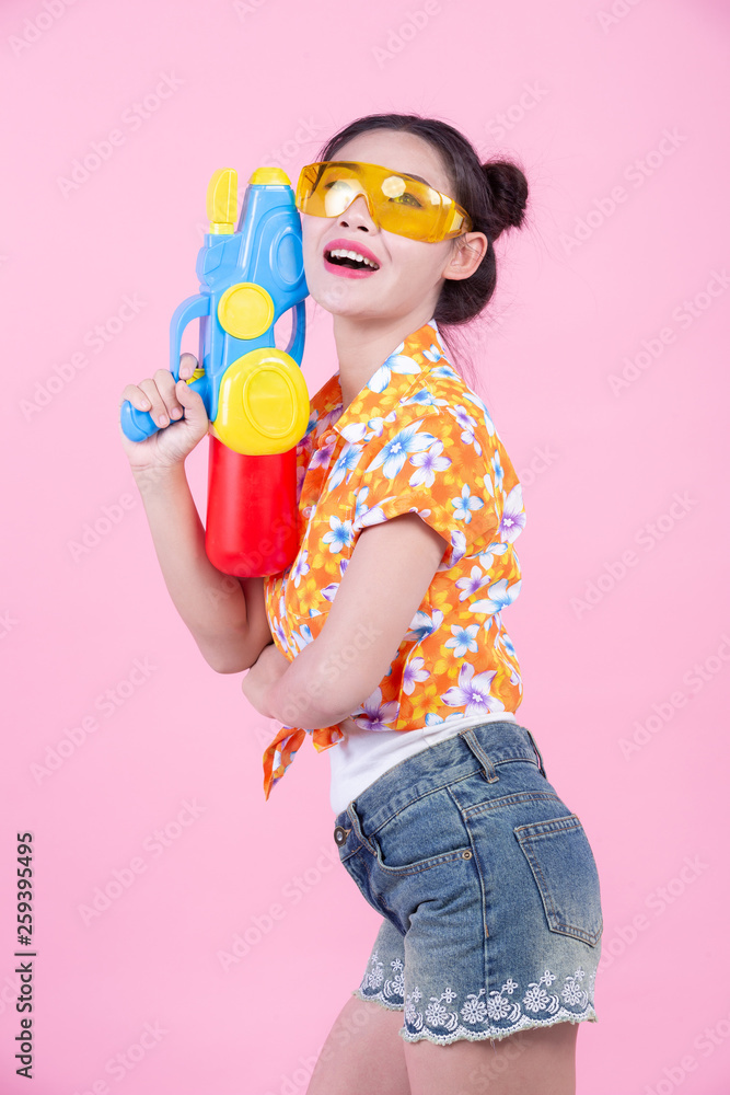 Happy girl holding a pink background water gun.